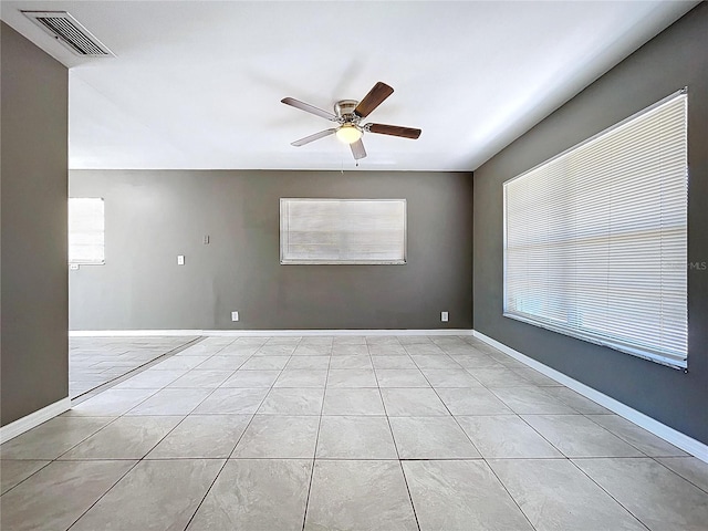 spare room featuring light tile patterned floors, visible vents, baseboards, and ceiling fan