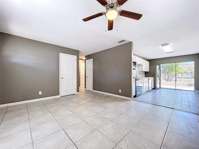 unfurnished living room with visible vents, baseboards, ceiling fan, light tile patterned floors, and a sink