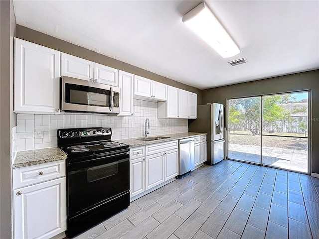 kitchen with visible vents, a sink, appliances with stainless steel finishes, white cabinetry, and backsplash