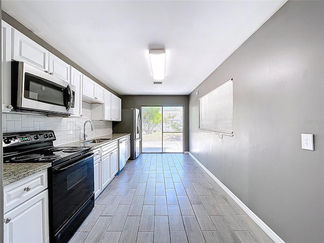 kitchen with wood finish floors, a sink, backsplash, white cabinetry, and stainless steel appliances