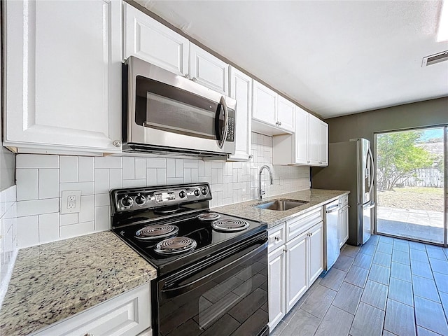 kitchen featuring light stone counters, visible vents, a sink, stainless steel appliances, and white cabinets