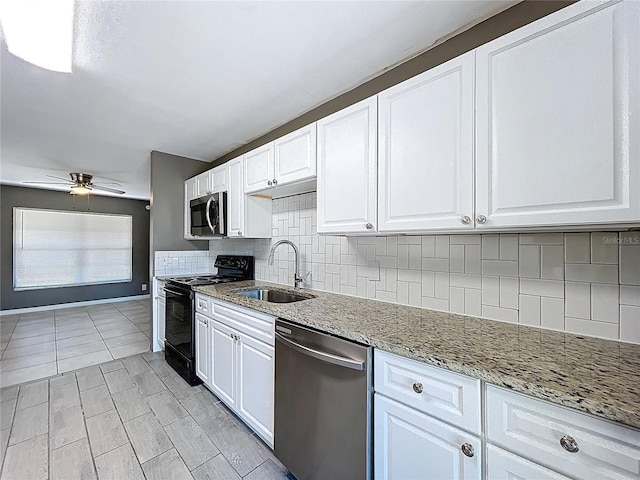 kitchen featuring a ceiling fan, a sink, white cabinetry, stainless steel appliances, and decorative backsplash