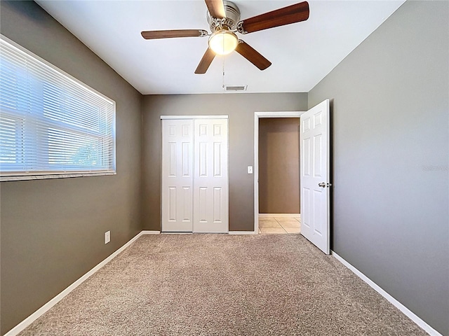 unfurnished bedroom featuring baseboards, a closet, light carpet, and visible vents