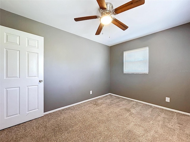 carpeted spare room featuring baseboards and ceiling fan