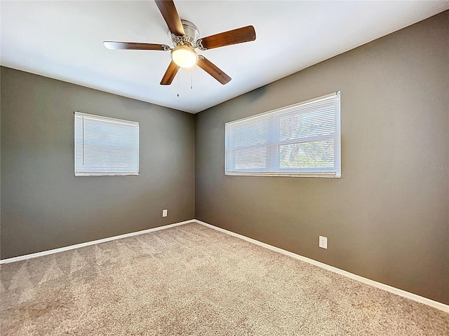 carpeted spare room with a ceiling fan and baseboards