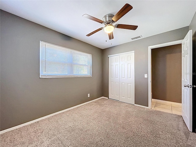 unfurnished bedroom featuring a ceiling fan, baseboards, visible vents, a closet, and light carpet