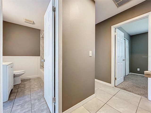 corridor featuring light tile patterned floors, visible vents, and baseboards