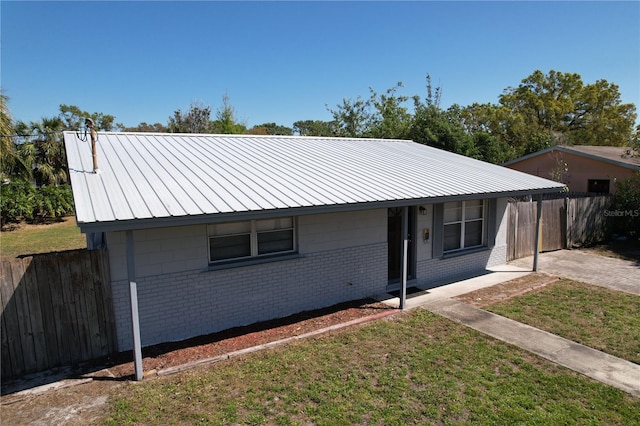 view of front of home featuring brick siding, covered porch, metal roof, and fence