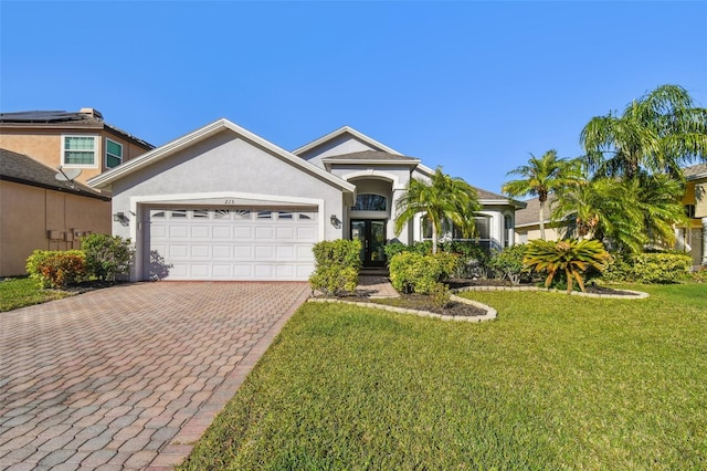 view of front of house with decorative driveway, a front lawn, an attached garage, and stucco siding