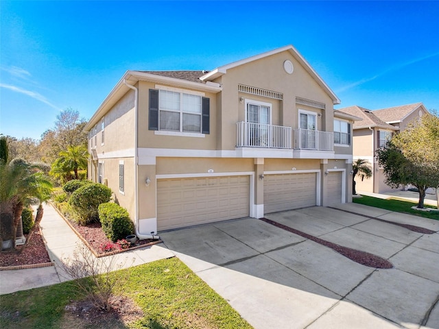 view of front facade with concrete driveway, a balcony, a garage, and stucco siding