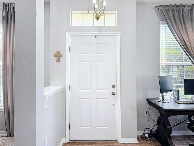 foyer entrance with baseboards, an inviting chandelier, and wood finished floors