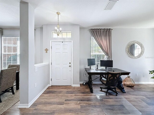 office space featuring an inviting chandelier, wood finished floors, visible vents, and baseboards