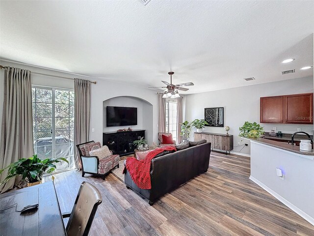 living area featuring a wealth of natural light, visible vents, and wood finished floors