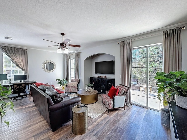 living area with visible vents, a textured ceiling, ceiling fan, and wood finished floors