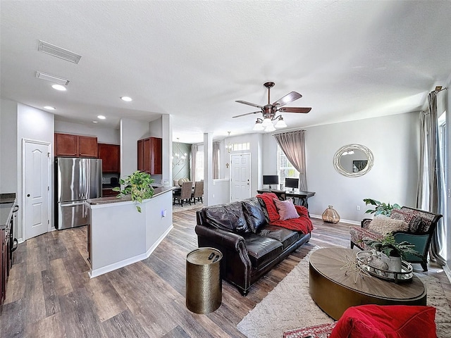 living area featuring visible vents, a textured ceiling, dark wood-style floors, and a ceiling fan