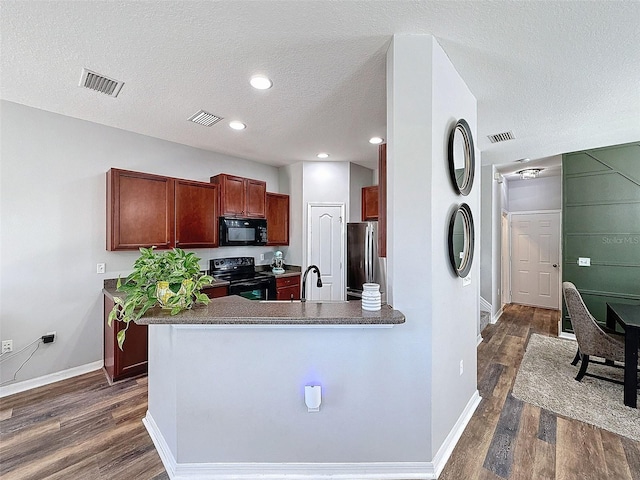 kitchen with visible vents, black appliances, and dark wood-type flooring