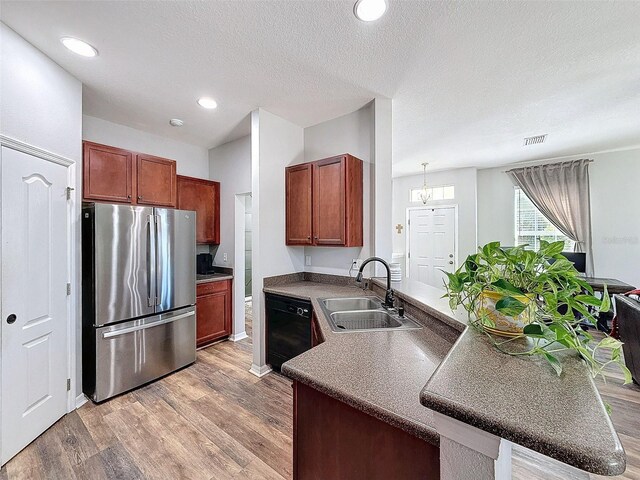 kitchen featuring light wood-type flooring, a sink, freestanding refrigerator, a peninsula, and dishwasher