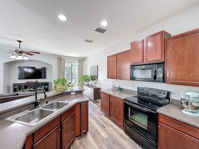 kitchen with visible vents, light wood-type flooring, black appliances, a sink, and open floor plan