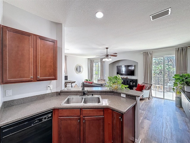 kitchen featuring visible vents, a sink, black dishwasher, open floor plan, and a peninsula