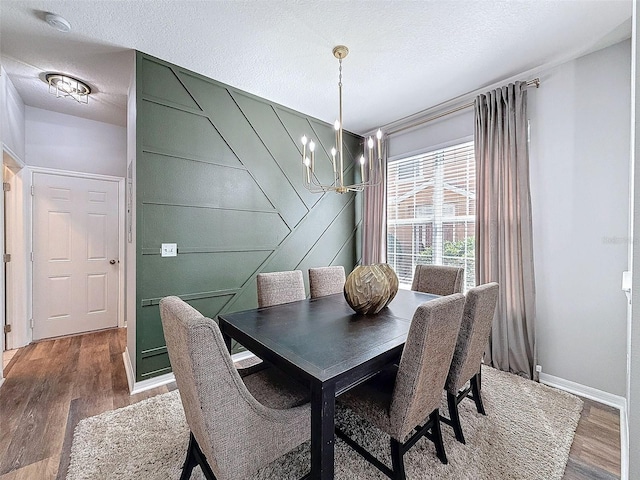 dining area featuring an inviting chandelier, wood finished floors, baseboards, and a textured ceiling