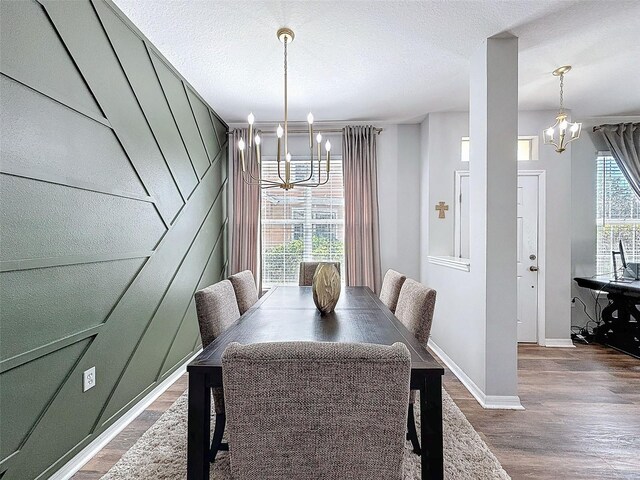 dining area featuring a chandelier, a textured ceiling, baseboards, and wood finished floors