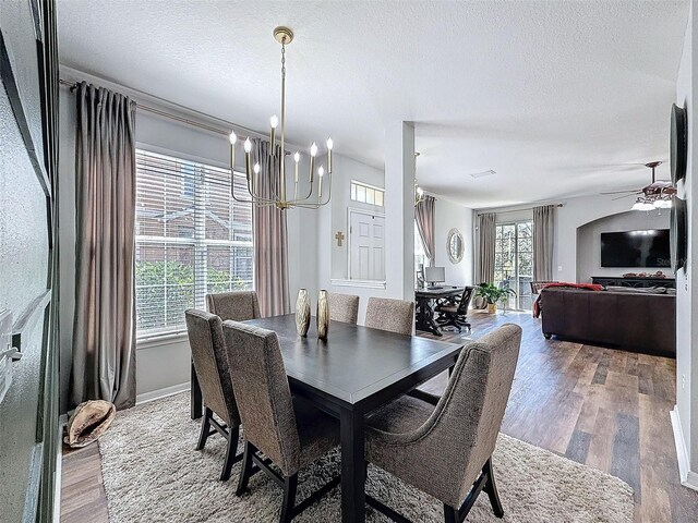 dining area with ceiling fan with notable chandelier, a textured ceiling, and wood finished floors