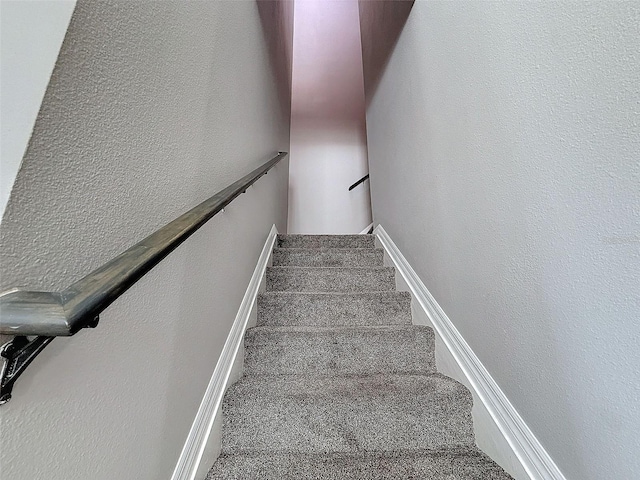 stairs with baseboards, carpet, and a textured wall