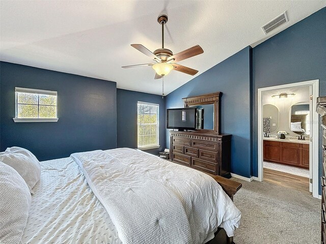 carpeted bedroom with baseboards, visible vents, ensuite bath, lofted ceiling, and ceiling fan