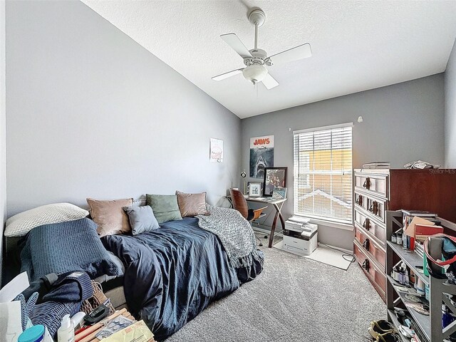 bedroom with a textured ceiling, ceiling fan, carpet flooring, and vaulted ceiling