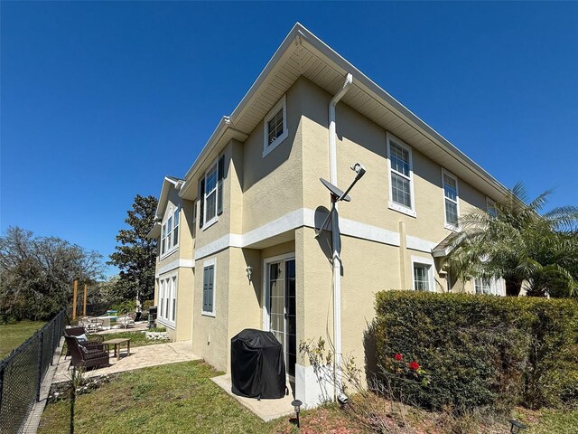 exterior space with a patio, fence, and stucco siding