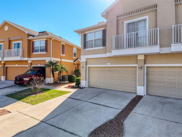 multi unit property featuring stucco siding, a garage, central AC unit, and concrete driveway