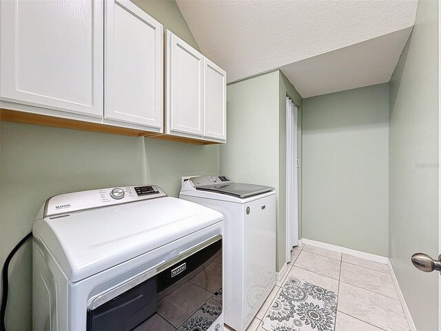 laundry area featuring baseboards, cabinet space, light tile patterned flooring, and washing machine and clothes dryer