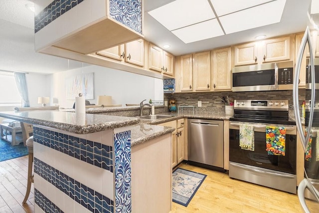 kitchen with light wood-style flooring, light brown cabinets, a sink, tasteful backsplash, and stainless steel appliances