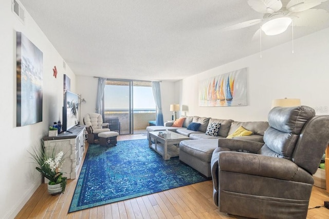 living area with visible vents, a textured ceiling, a ceiling fan, and hardwood / wood-style flooring