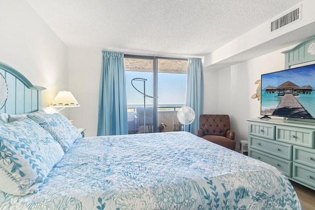 bedroom featuring visible vents, a textured ceiling, and wood finished floors