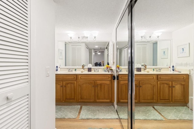 full bathroom with a textured ceiling, wood finished floors, a closet, a chandelier, and vanity