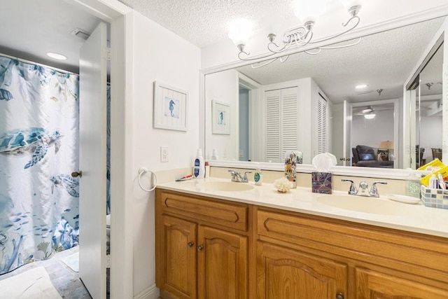 bathroom featuring a sink, a ceiling fan, a textured ceiling, and double vanity