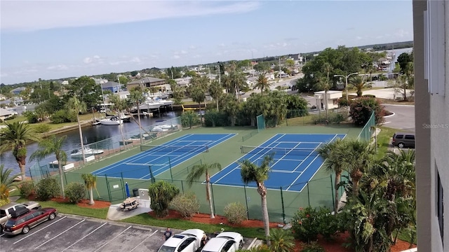 view of tennis court featuring a water view and fence