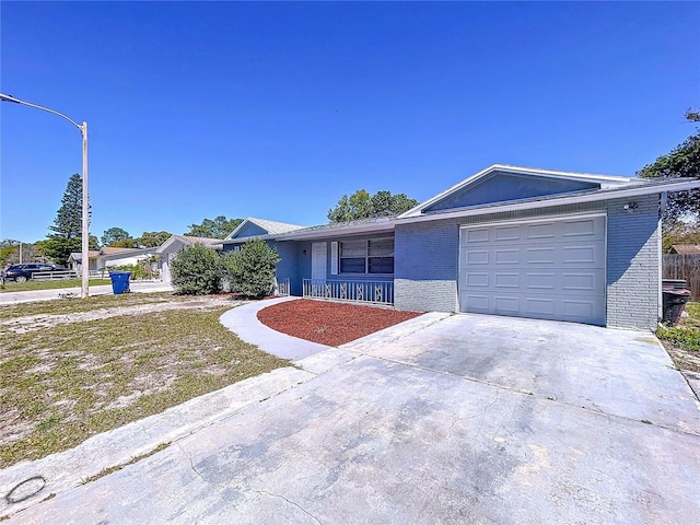 ranch-style home with a garage, brick siding, a porch, and driveway