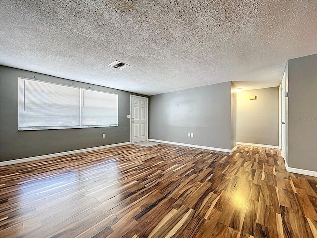 spare room with visible vents, a textured ceiling, baseboards, and wood finished floors