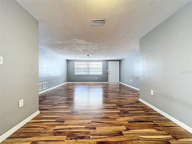 empty room featuring visible vents, baseboards, and wood finished floors