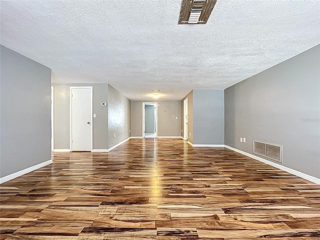 unfurnished room featuring wood finished floors, visible vents, and baseboards