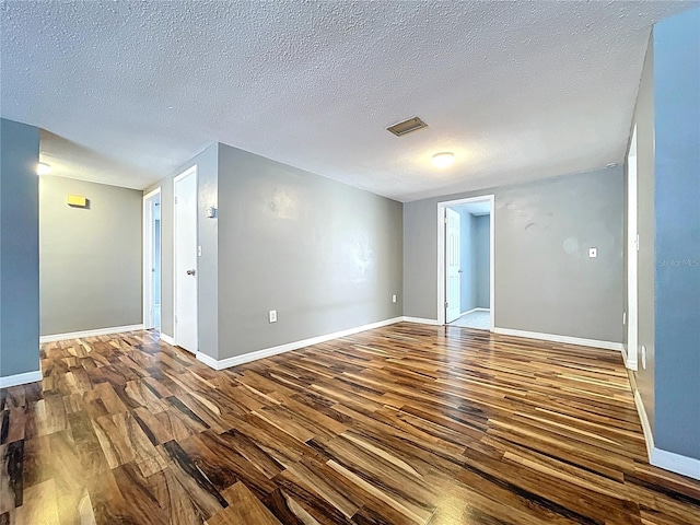 unfurnished room with visible vents, baseboards, a textured ceiling, and wood finished floors