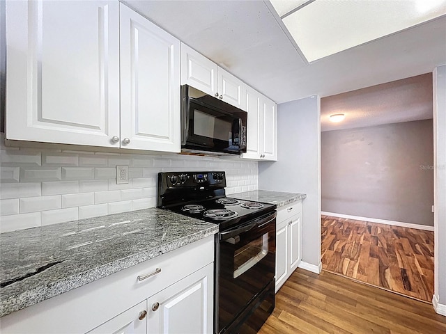 kitchen with black appliances, tasteful backsplash, wood finished floors, white cabinetry, and baseboards