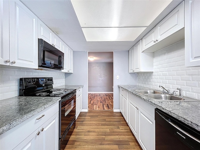 kitchen with baseboards, dark wood finished floors, a sink, black appliances, and white cabinets