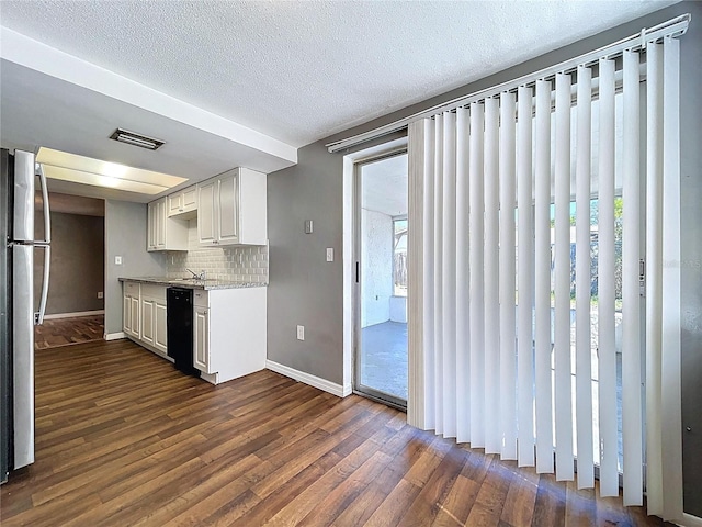 kitchen featuring visible vents, dark wood finished floors, freestanding refrigerator, dishwasher, and tasteful backsplash