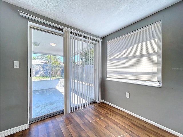 doorway featuring dark wood-style floors, baseboards, and a textured ceiling