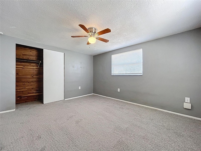 unfurnished bedroom featuring a textured ceiling, carpet, a closet, and ceiling fan