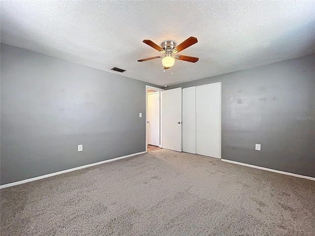 unfurnished bedroom with visible vents, a textured ceiling, a closet, carpet floors, and ceiling fan