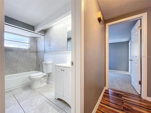 full bath with vanity, a wainscoted wall, a textured ceiling, shower / tub combination, and toilet